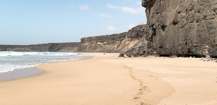 Dunkle Felsvorsprünge am weitläufigen Playa de Corralejo auf Fuerteventura.
